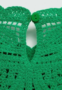 Grüner gehäkelter Stoff mit einem filigranen Muster, das eine gewellte Kante und einen grünen Knopfverschluss am Ausschnitt aufweist.