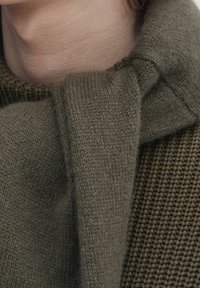 Maglione a maglia verde oliva con una trama strutturata e spessa e un colletto a sciarpa drappeggiato, realizzato in materiale morbido simile alla lana.
