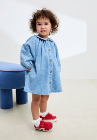 Lyseblå blomsterprint kjole med knapper, pufærmer, lommer og krave. Kombineret med røde sneakers og hvide blondekantsokker.