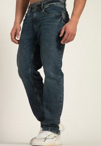 Donkerblauwe spijkerbroek met een recht model, voorzien van een knoop- en ritssluiting, en vijf zakken. Draag het met witte sneakers.