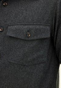 Dark gray wool shirt with two chest pockets, button closure, and black plastic buttons. Features a soft, textured finish.