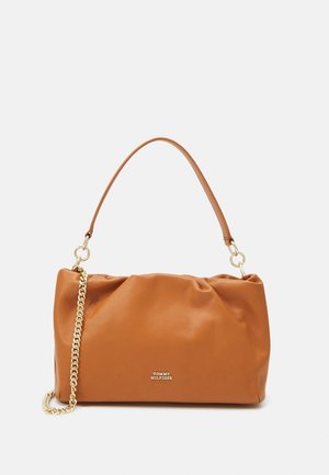 Sac à main en cuir marron avec une anse courte et un détail en chaîne dorée, petit logo Tommy Hilfiger centré sur le devant.