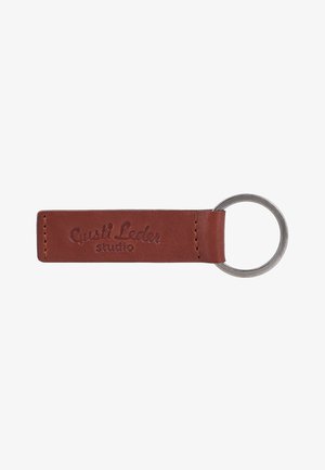 Brauner Leder-Schlüsselanhänger mit Metallring und dem eingeprägten Text "Gusti Leder studio" auf dem Lederband.