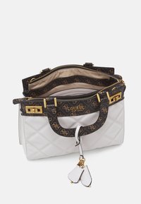 Sac à main beige matelassé avec des accents imprimés en noir, quincaillerie dorée et un détail de porte-clés. Comprend plusieurs compartiments intérieurs.