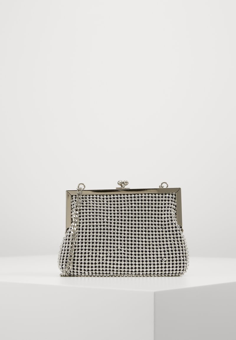 Kleine zilveren avondtas van mesh met metalen frame, kiss-lock sluiting en een zilveren kettingriem, rustend op een wit oppervlak.