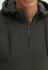 Sudadera de felpa de media cremallera en gris oscuro con capucha ajustable. Presenta cordones naranjas en contraste y acentos impresos en la cremallera.