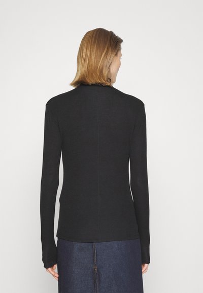 Cămașă neagră cu mânecă lungă, realizată dintr-un material moale, cu un design ajustat, decolteu rotund și manșete atașate, asortată cu o fustă din denim închis.