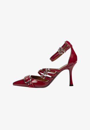 Zapato de tacón alto de charol rojo con punta afilada, múltiples correas, detalles de hebilla plateada y un esbelto tacón de aguja.