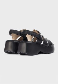 Sandalias de plataforma negras con acabado en cuero texturizado, múltiples correas entrelazadas y una suela exterior de goma resistente.