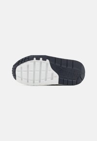 Suola di sneaker in gomma blu scuro con intersuola bianca. Presenta motivi scanalati e il logo "AIR" impresso sul lato per trazione e supporto.