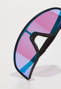 Lunettes de sport avec une monture noire, dotées de verres bicolores en rose et bleu, et d'un design enveloppant. Poignées en caoutchouc texturé sur les côtés.