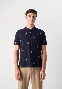 Marine polo skjorte laget av bomull, med rød krage og små fuglebroderier over hele stoffet. Korte ermer, klassisk passform.