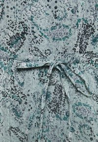 Ljusgrön klänning med ett blommönster i mörkare nyanser. Inkluderar en knytdetalj vid midjan, tillverkad av ett texturerat tyg.