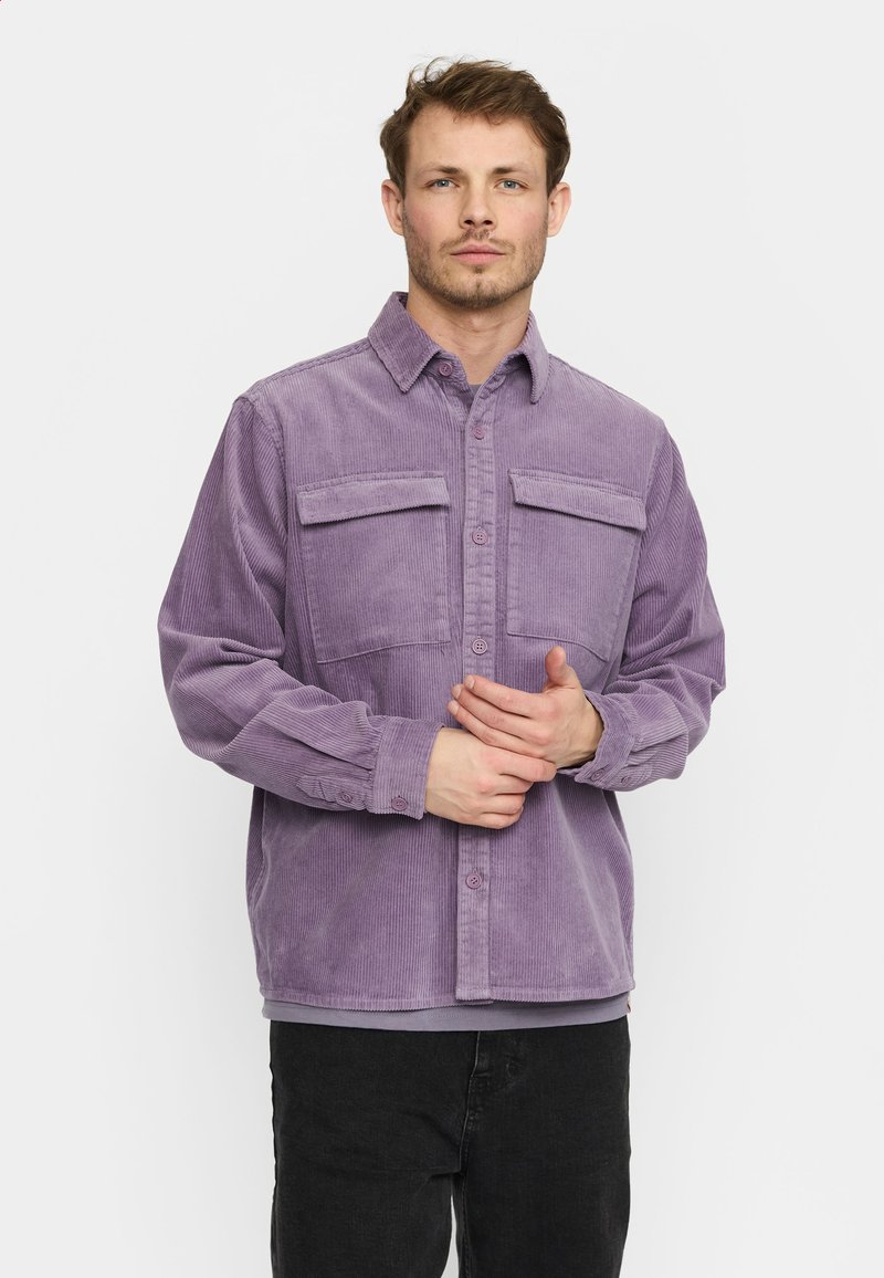 Paarse corduroy shirt met twee borstzakken, knoopsluiting aan de voorkant en lange mouwen, gedragen met zwarte broeken. Gestructureerde stof met ribbelpatroon.