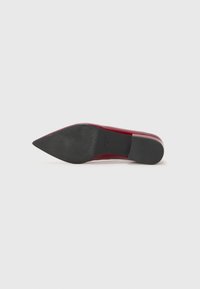 Red patent leather high-heeled shoe with a pointed toe. The sole is black, textured, and slightly rounded at the back.