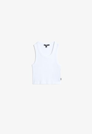 Débardeur en coton blanc avec une texture côtelée, un col rond et des bretelles larges. Il présente une petite étiquette de marque sur l'ourlet.
