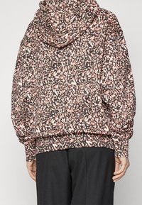 Bluza z kapturem w czarno-różowo-białą nakrapianą wzór. Charakteryzuje się luźnym krojem oraz ściągaczami w dolnej części i przy rękawach. Miękka, teksturowana tkanina.