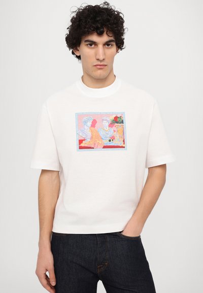 Witte katoenen t-shirt met een kleurrijke grafische print van twee figuren, met een lichtblauwe rand rond het ontwerp. Korte mouwen.