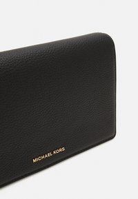 Black textured leather wallet with a sleek design. Features a gold "MICHAEL KORS" logo accent at the bottom.