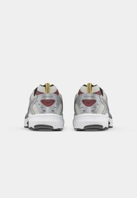 Men's running shoes featuring a mesh upper in gray, black accents, red details, and a white midsole with a textured sole. Yellow pull tab at the heel.
