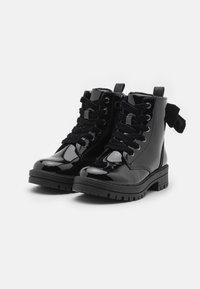 Bottines en cuir verni noir à bout rond, avec un laçage, des accents en daim noir et une semelle en caoutchouc texturé pour une meilleure traction.