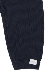 Marine gebreide broek met een gestructureerde afwerking en geribbelde boorden; voorzien van een klein wit label met "noppies" aan de onderkant.