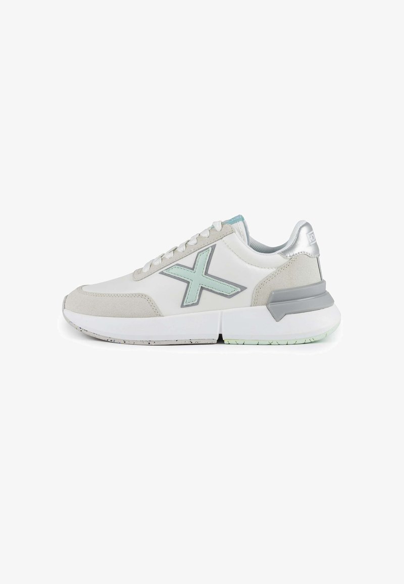 White athletic shoes featuring a suede gray toe cap, light blue accents, a silver heel counter, and a thick white sole.