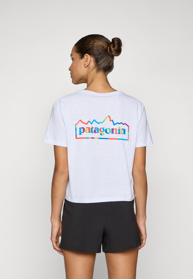 T-shirt blanc à manches courtes avec un graphique coloré "Patagonia" et un design de montagne au dos. Coupe décontractée, avec une texture légère et douce.