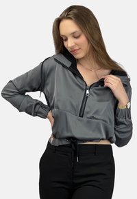 Szara skórzana kurtka o krótkim kroju, wykonana z błyszczącego materiału, z pół-zamkiem, elastycznymi mankietami i regulowanym dołem. Minimalistyczny design z kontrastującymi akcentami.