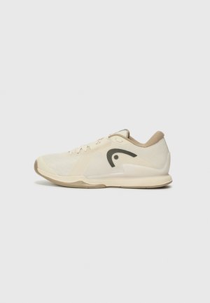 Beige sportieve schoen met bovenwerk van mesh, ronde neus en een rubberen zool. Heeft een donker logo aan de zijkant en een gestructureerde achterkant van de hak.