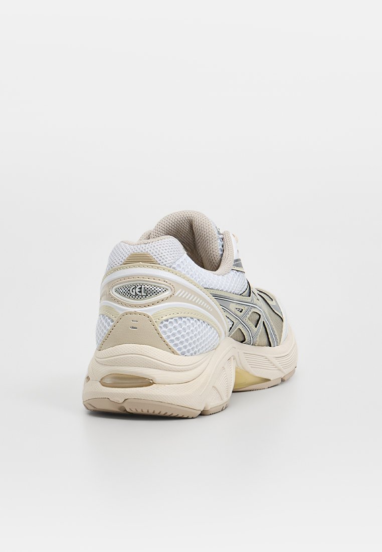 Witte en beige sneaker met een bovenwerk van mesh en synthetisch materiaal, een gevoerde hak, een gladde textuur en een rubberen zool. Beschikt over een reflecterende accenten en logo.
