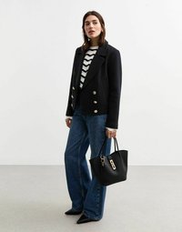 Svart dubbelknäppt kavaj i ullblandning med stora knappar, parat med en randig stickad topp, vida blå jeans och en svart handväska.