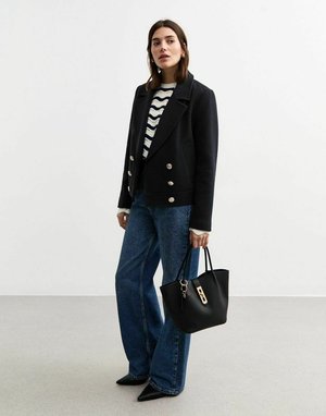 Zwart dubbelzijdig wollen jas met grote knopen, gecombineerd met een gestreept gebreid shirt, wijde blauwe jeans en een zwarte handtas.