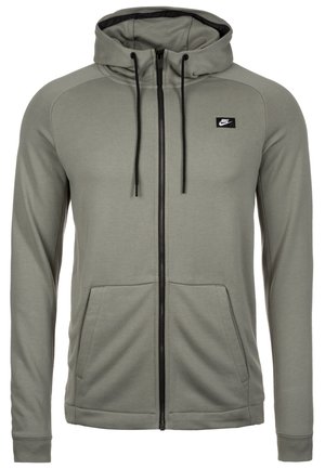 Lysegrå Nike hættetrøje med fuld lynlås, sorte snore, forlommer og et lille sort Nike-logo på venstre bryst.