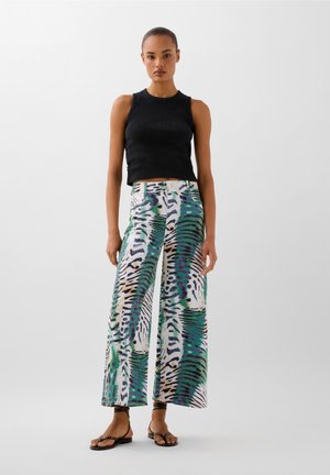 Černý žebrovaný crop top a kalhoty s širokými nohavicemi s potiskem zvířat v zelené, fialové a černé barvě. Hladká tkanina, uvolněný střih a minimální hardware.