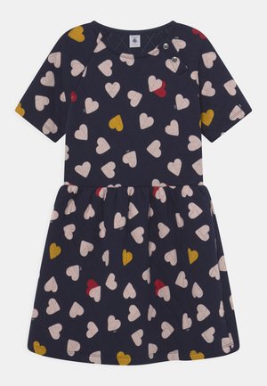 Vestido de manga corta en color navy con textura acolchada, que presenta pequeños patrones de corazones en rosa, rojo, amarillo y blanco. Detalle de botón a presión en el escote.