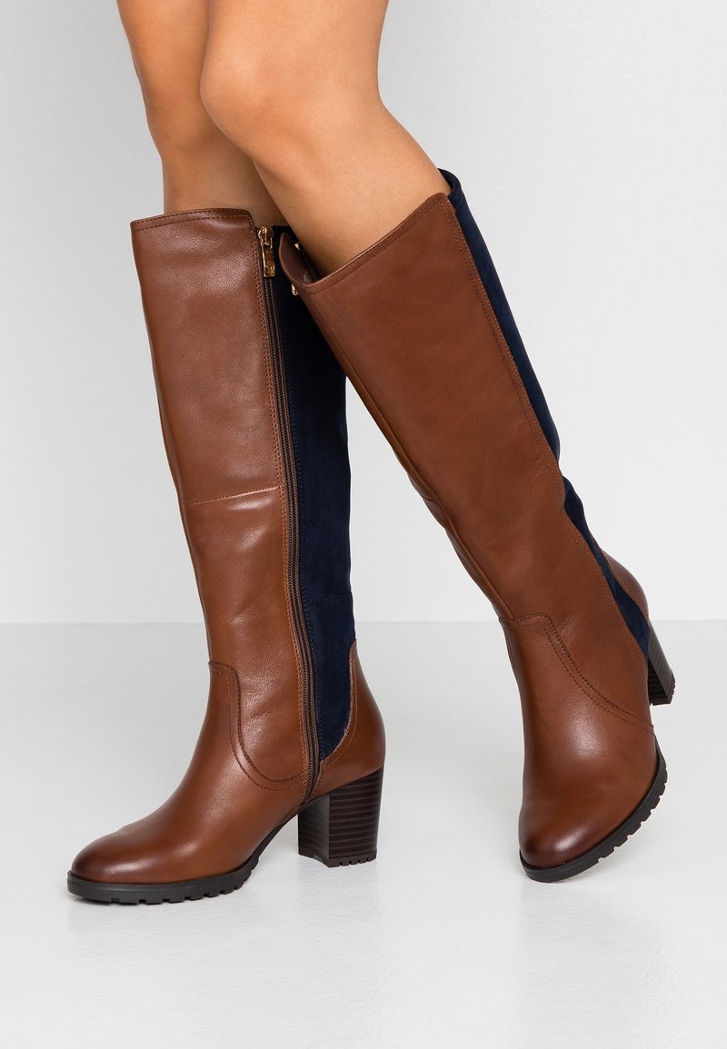 Botas altas hasta la rodilla de cuero marrón y ante azul marino con tacón grueso, que cuentan con una cremallera lateral y suela texturizada.