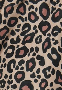 Panterprint stof met grote zwarte vlekken en roze accenten op een beige achtergrond. Glad textuur met een subtiele glans.