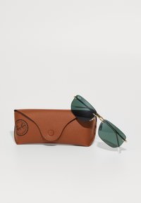 Ray-Ban žalių atspalvių stačiakampiai akiniai nuo saulės su auksiniu rėmu, atsigulę ant rudos odinės dėžutės su mygtuko uždarymu ir logotipo antspaudu.