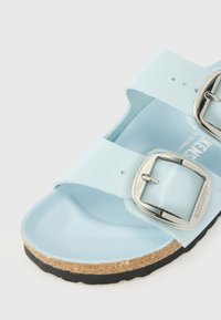 Sandale bleu clair avec deux larges brides avec boucles argentées et une semelle intérieure en liège avec une semelle noire.