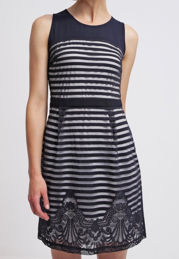 Robe sans manches bleu marine avec rayures horizontales noires et blanches, empiècement uni bleu marine, taille ajustée et bordure en dentelle florale à l'ourlet.