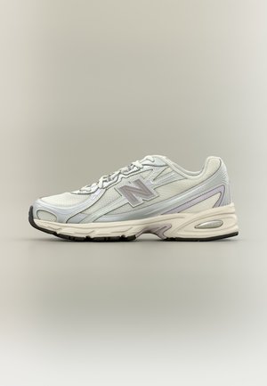 Weißer und grauer sportlicher Laufschuh mit gepolsterter Sohle, Mesh-Obermaterial, Schnürverschluss und dem gebrandeten "N"-Logo an der Seite.