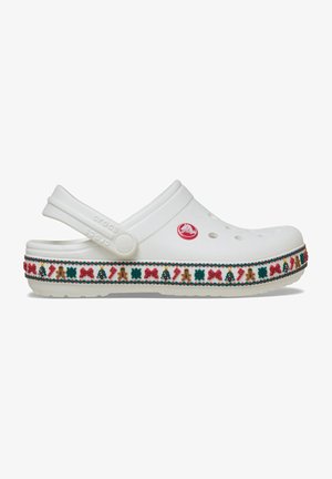 Weiße Crocs mit einem flachen Design, das festliche rote, grüne und goldene Verzierungen am Rand aufweist, einschließlich winterlichen Motiven.