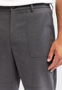 Gray tailored trousers made of textured fabric. Features a button closure, side pockets, and a sleek, straight-leg design.