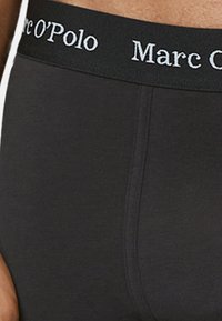 Boxer briefs neri da uomo con un tessuto morbido e un cinturino elastico caratterizzato da testo del logo bianco. La vestibilità è aderente, con un design senza cuciture.