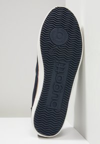 Zapatilla navy con suela de goma texturizada, media suela blanca y detalles de logotipo en relieve. El patrón de banda de rodadura único mejora el agarre y la estabilidad.