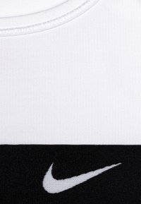 Nike tank top, millel valge ülemine osa ja must alumine osa, valmistatud siledast kangast, mustal osal valge logo.