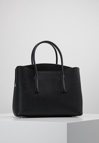 Borsa nera in pelle con forma strutturata, finitura testurizzata, due manici superiori e dettagli in metallo dorato. Nessun logo o motivo visibile.