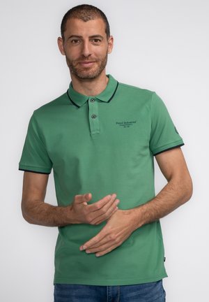 Groene polo met een getailleerd design, korte mouwen en marineblauwe accenten bij de kraag en mouwranden. Bevat een logo op de borst.