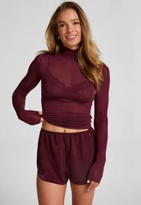 Bordeauxrotes Langarmshirt mit Stehkragen und transparentem Stoff, kombiniert mit passenden Shorts mit elastischem Bund.